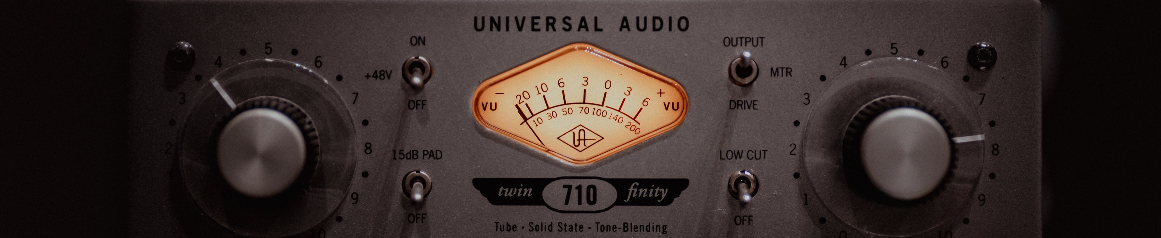 Close-up of a Universal Audio 710 Twin-Finity preamp with a glowing VU meter